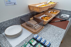 Una mesa de buffet con pan, bollería y productos lácteos.