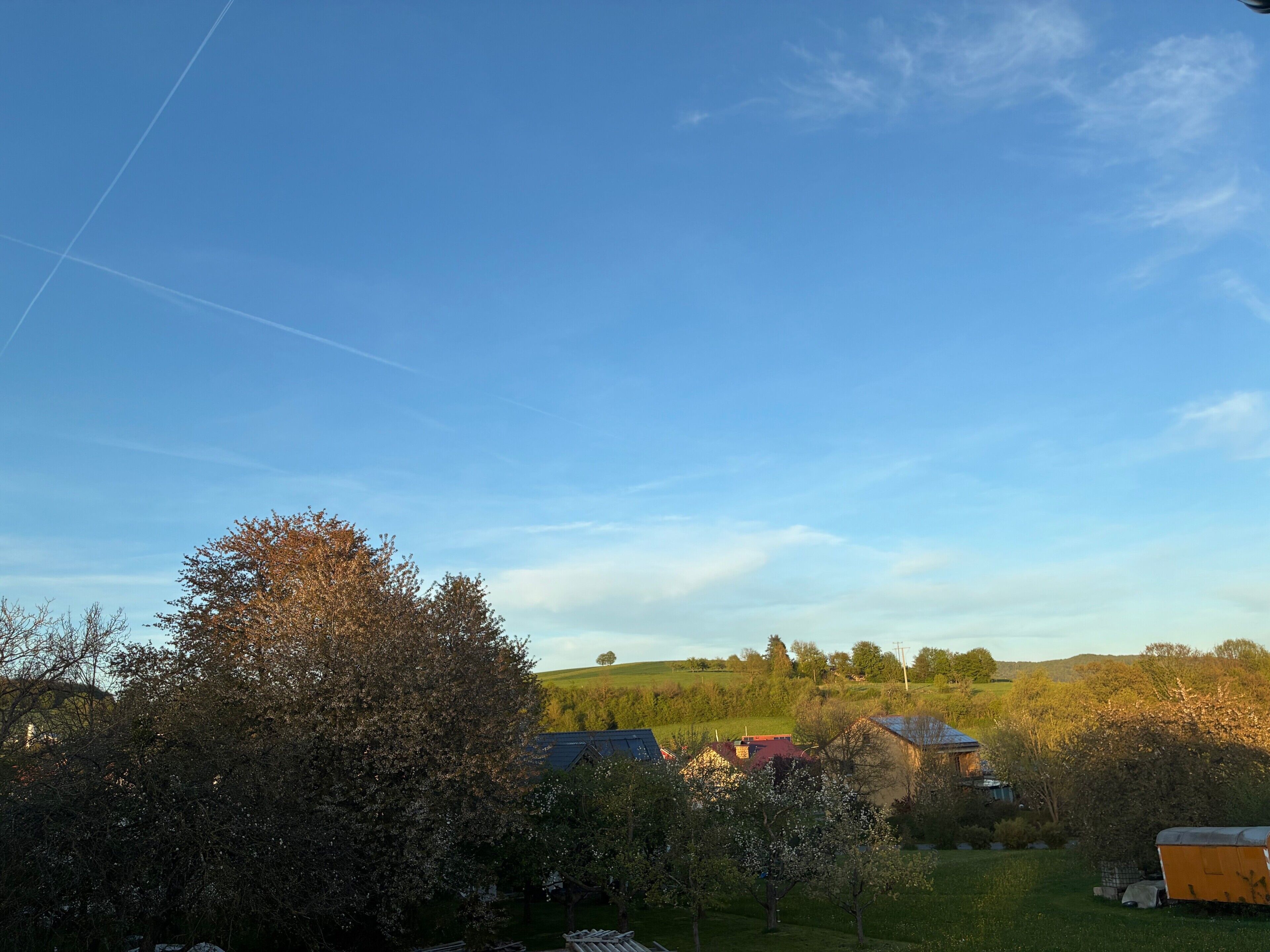 Paisaje rural con casas, árboles y cielo despejado.