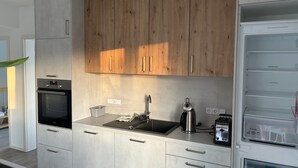 A modern kitchen with wooden cabinets, a built-in oven, a sink, and a coffee machine. - Apartment 'Hedwig Und Anna' with Balcony and Wi-Fi (Zapfendorf)