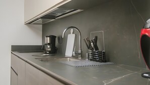 Uma cozinha moderna com uma pia de aço inoxidável, uma cafeteira e um porta-facas.