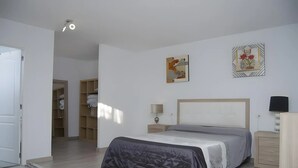 Quarto com cama, mesa de cabeceira, abajur e guarda-roupa.