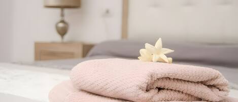 A neatly made bed with folded towels and a decorative flower.