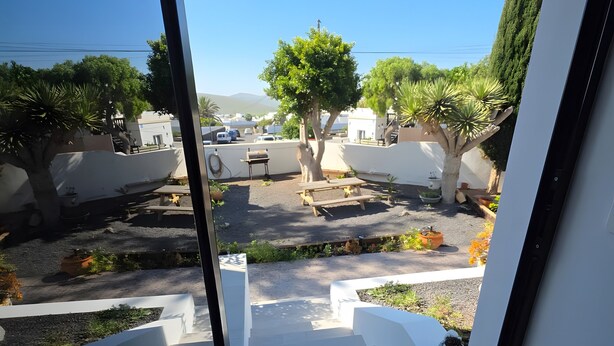 A view from a window overlooking a courtyard with a staircase leading outside, surrounded by trees and a parked vehicle. - Alunita Room – Cozy Retreat in Peaceful Nazaret, Lanzarote (Nazaret)