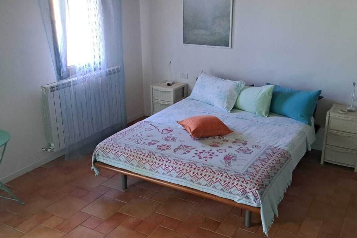 Une chambre à coucher avec un lit, une petite table, une chaise, un radiateur et une fenêtre.