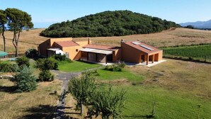 A modern house with a sloped roof, a covered patio, and a view of a hilly landscape. - Studio apartments near Baratti Bay (Toscana)