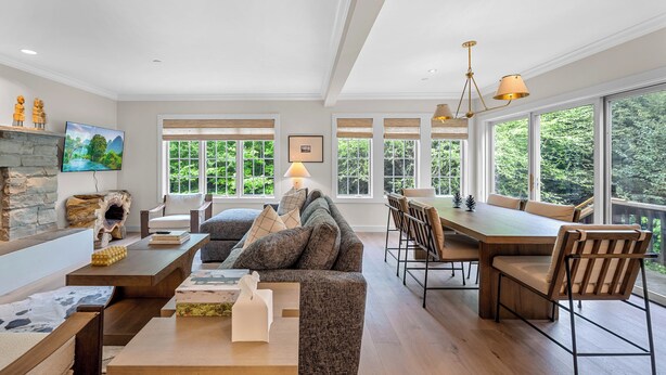 A spacious living area with a fireplace, a large sofa, a dining table, and a view of the outdoors. - Topnotch Luxury Retreat | Sleeps 12 • Pet Friendly • Game Room (Stowe)