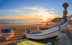 Ein Strand mit Booten und einem Sonnenuntergang.