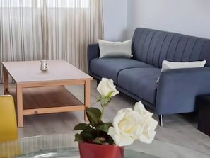 A living room with a sofa, a coffee table, and a potted plant.