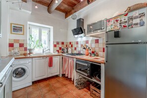 Eine kleine Küche mit Waschmaschine, Backofen und Mikrowelle.