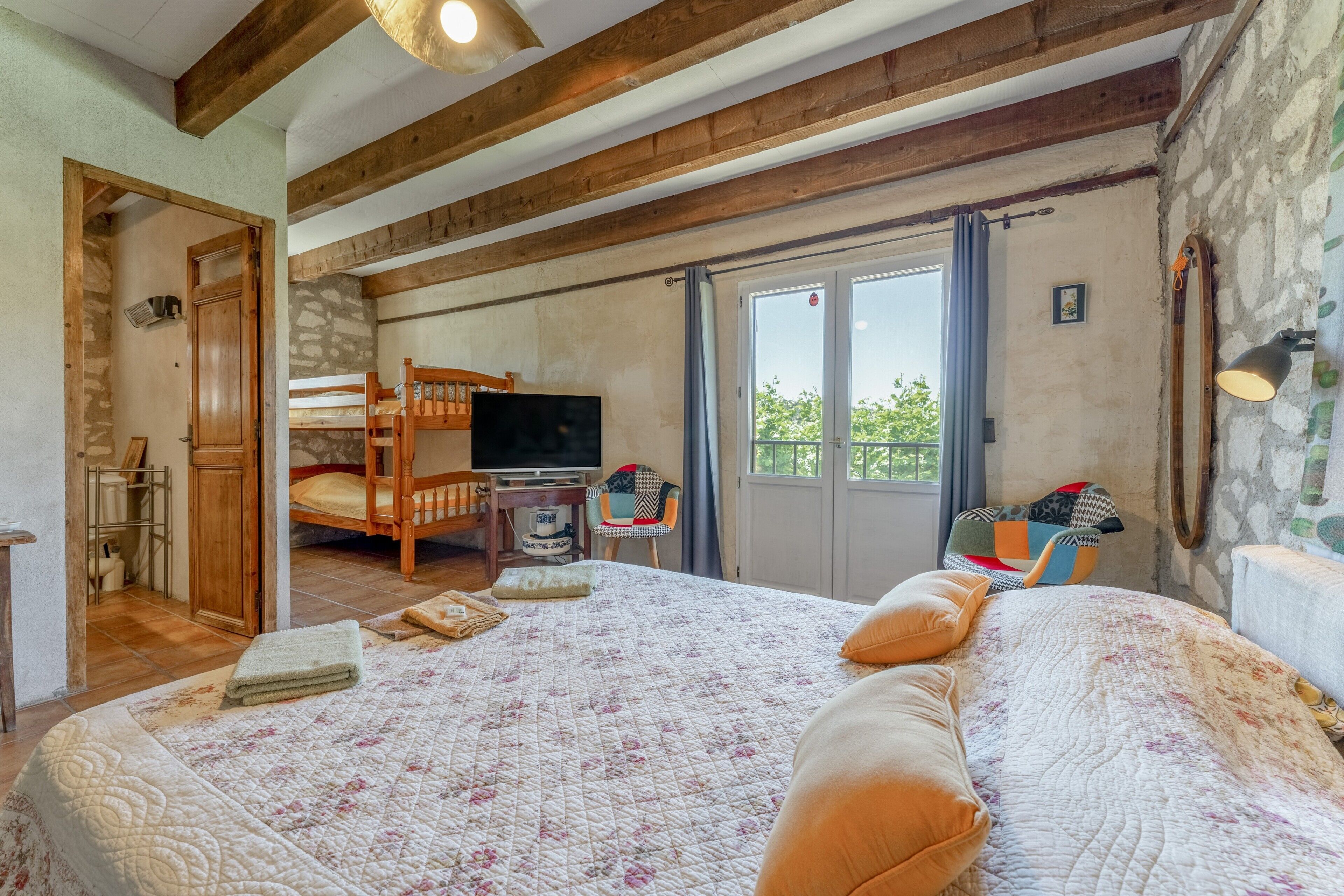 Une chambre avec un grand lit, un bureau en bois, une télévision et un balcon avec vue.