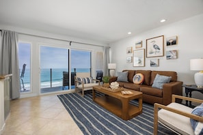 A living room with a sofa, coffee table, and a view of the ocean through large windows. - Solana Sunshine! Oceanfront Condo in Solana Beach with Tesla Charger (Solana Beach)