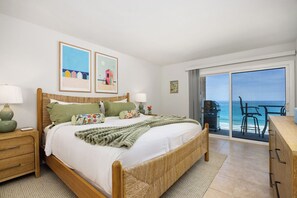 A bedroom with a bed, bedside tables, a balcony with a view of the ocean, and artwork on the wall. - Solana Sunshine! Oceanfront Condo in Solana Beach with Tesla Charger (Solana Beach)