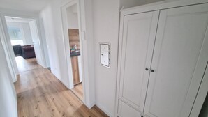 A hallway with wooden flooring, a white wardrobe, and a visible electrical outlet. - Cozy guest rooms in a modern, renovated apartment (Schwäbisch Gmünd)