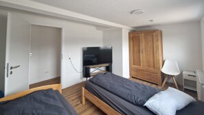 A room with a bed, a TV, a wardrobe, and a desk with a lamp. - Cozy guest rooms in a modern, renovated apartment (Schwäbisch Gmünd)