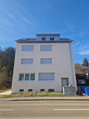 Ein mehrstöckiges Gebäude mit Flachdach, großen Fenstern und einer sichtbaren Garagentür.