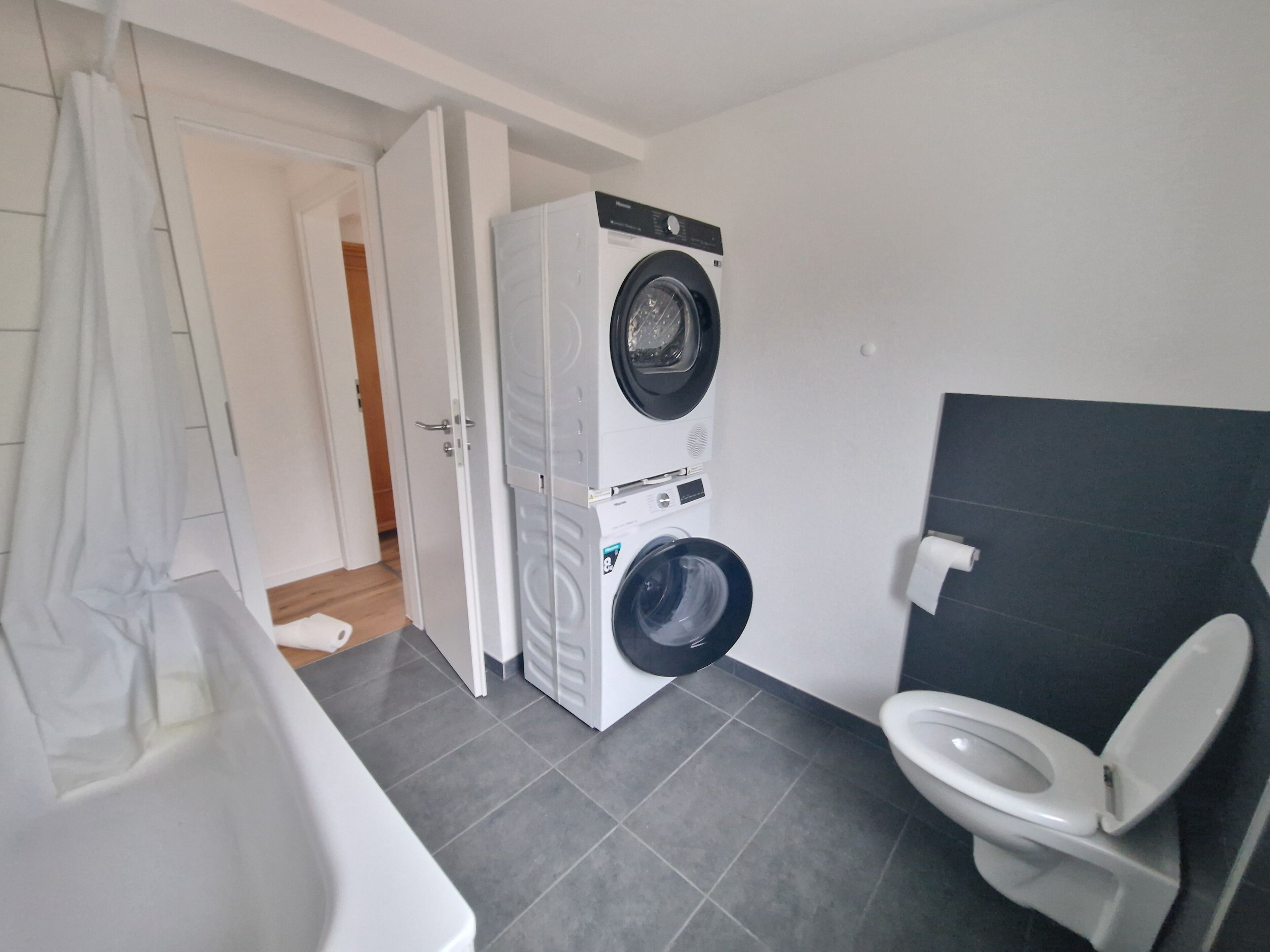 Ein kleines Badezimmer mit Waschmaschine, Toilette und Duschbereich.