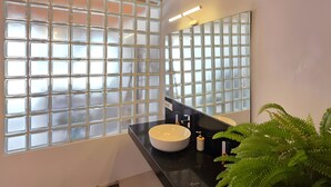 Un bagno con un'ampia finestra, un lavandino rotondo, uno specchio e un lampadario.