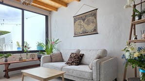 Un accogliente soggiorno con soffitto in legno, una mappa del mondo appesa al muro, un divano con cuscini decorati, un tavolino da caffè e diverse piante in vaso.