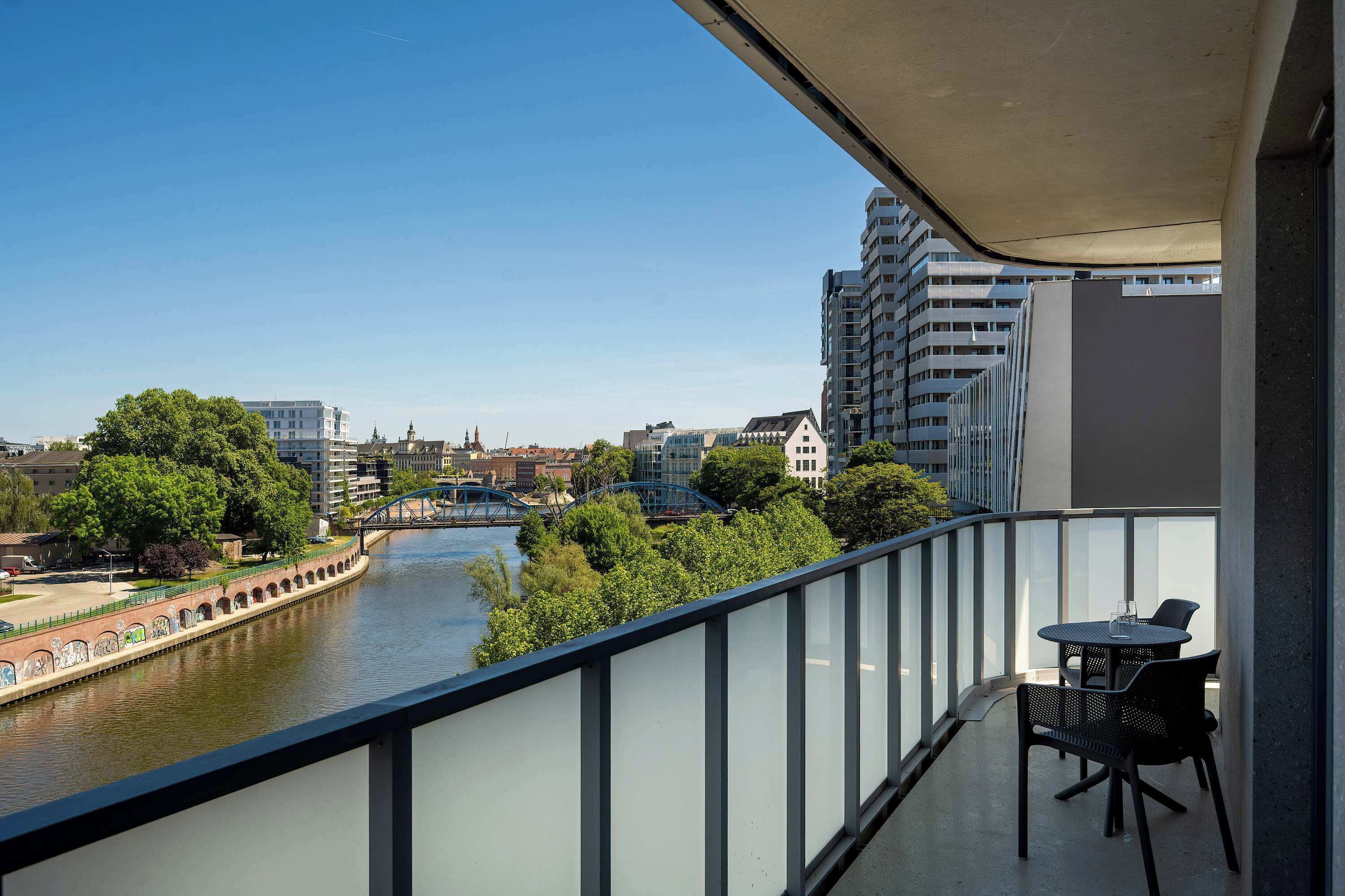Un balcon avec vue sur une rivière, un pont et des bâtiments.