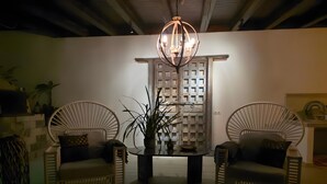 A room with two wicker chairs, a table with a vase, and a decorative wall panel.