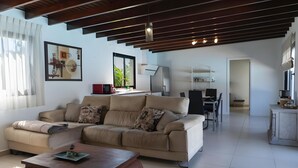 A living room with a sofa, coffee table, and a dining area with chairs and a table.