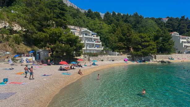 A beach with clear water, people sunbathing, and buildings in the background. - Holiday Home Stari Dom Ivkošic by Villas Guide (Zmijavci)