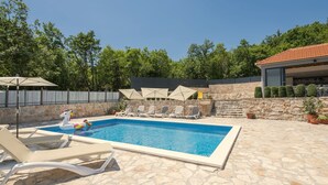 A swimming pool with lounge chairs and umbrellas, surrounded by stone walls and trees. - Holiday Home Stari Dom Ivkošic by Villas Guide (Zmijavci)