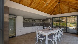 A modern kitchen with white cabinetry, a large island with seating, and a view through glass doors to an outdoor area.