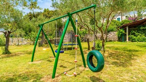 A playground with swings and a tire swing. - Guest House Sunset Kalla by Villas Guide (Rab)