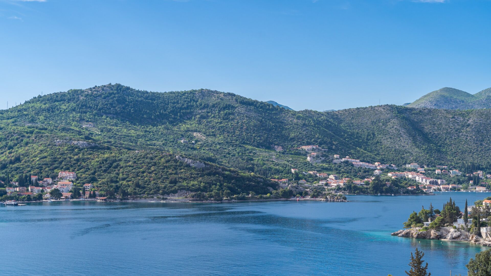 A coastal town with buildings on the hillside and a body of water in the foreground.