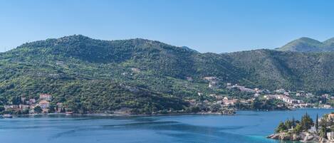 A coastal town with buildings on the hillside and a body of water in the foreground.