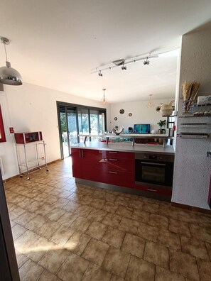 Eine geräumige Küche mit einer großen Kochinsel, einem Einbauofen und einer Schiebetür zum Balkon.