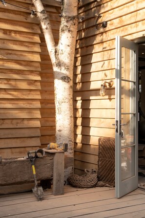 A wooden cabin with a glass door, a shovel, and a rope on the deck. - Period Townhouse - Garden Gym Playroom (London)