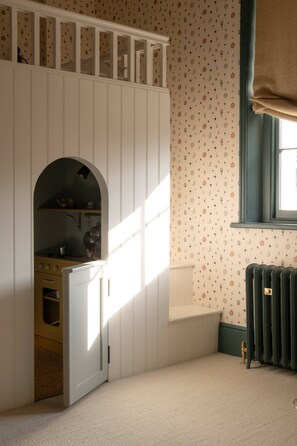 A room with a built-in kitchen, a window with curtains, and a radiator. - Period Townhouse - Garden Gym Playroom (London)