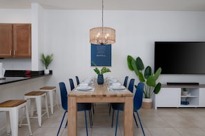 Un espace repas moderne avec une table en bois, des chaises bleues et un luminaire suspendu.