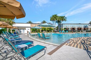 A pool area with lounge chairs and umbrellas, a clear sky, and palm trees. - 20 Mins to Disney Arcade Battles Mini Golf (Davenport)
