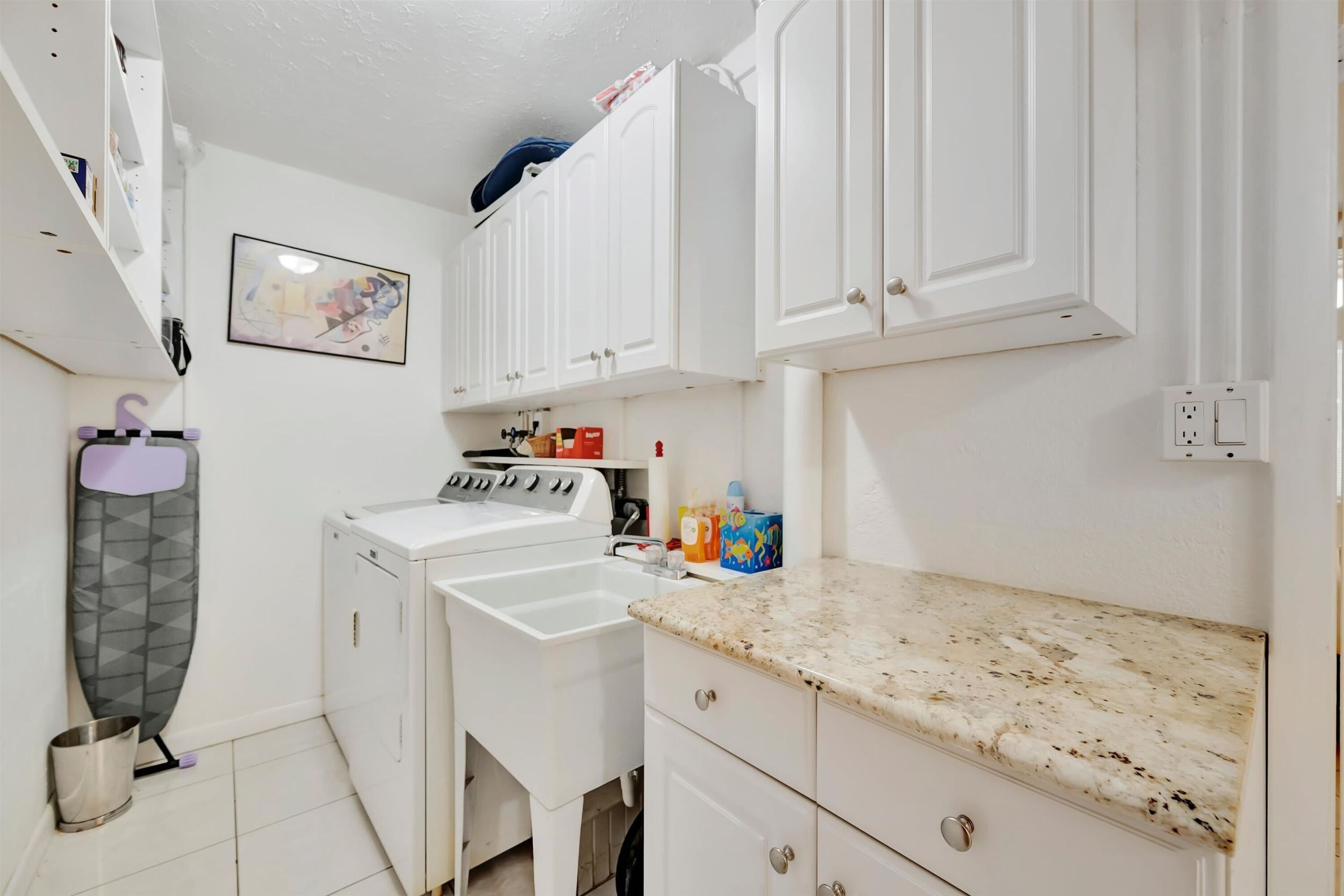 A laundry area with a washing machine, a drying rack, and a sink.