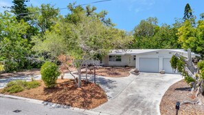 A single-story house with a garage, surrounded by trees and a driveway. - Coastal Home w Hot Tub Firepit and Music Lounge (Siesta Key)