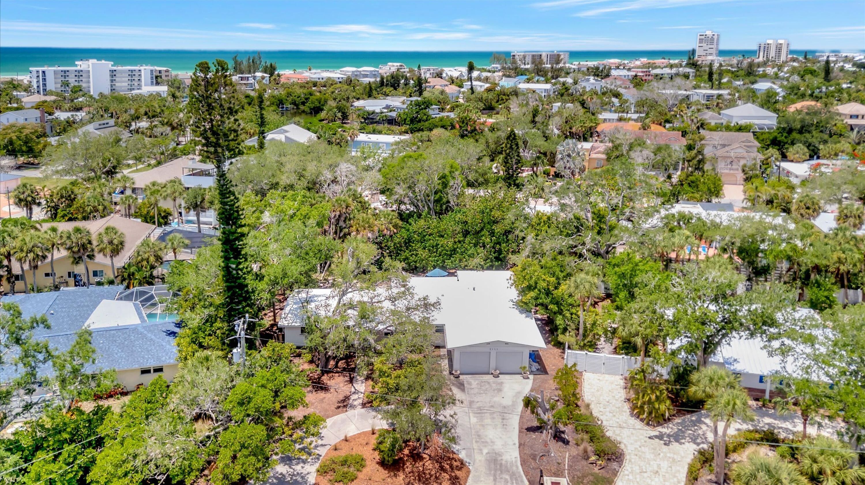 A residential area with houses, trees, and a beach in the background.