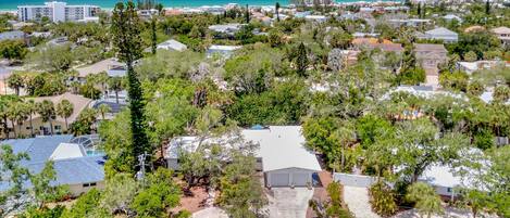 A residential area with houses, trees, and a beach in the background.