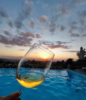 A glass of white wine held over a swimming pool with a sunset in the background. - Villa Calvina - Charm-filled Villa With Large Pool in Calvi D Umbria Between Rome and Tuscany (Calvi di Umbria)