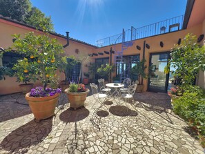 A courtyard with potted plants, a tiled floor, and outdoor furniture. - Villa Calvina - Charm-filled Villa With Large Pool in Calvi D Umbria Between Rome and Tuscany (Calvi di Umbria)