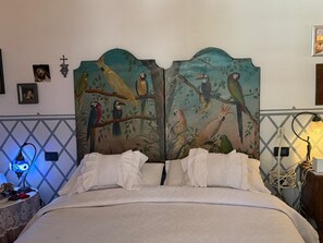 A bed with white linens, a nightstand with a lamp, and a wall with a bird mural. - Villa Calvina - Charm-filled Villa With Large Pool in Calvi D Umbria Between Rome and Tuscany (Calvi di Umbria)