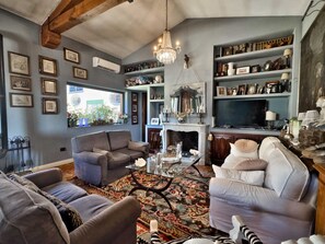 A living room with a fireplace, a chandelier, and a bookshelf filled with books and decorative items. - Villa Calvina - Charm-filled Villa With Large Pool in Calvi D Umbria Between Rome and Tuscany (Calvi di Umbria)
