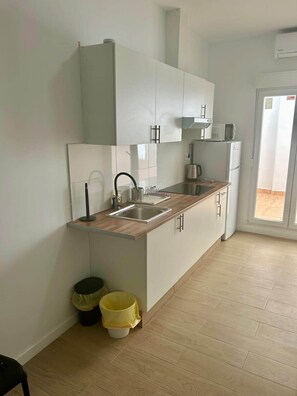 Een moderne keuken met witte kasten, een roestvrijstalen spoelbak en een magnetron.