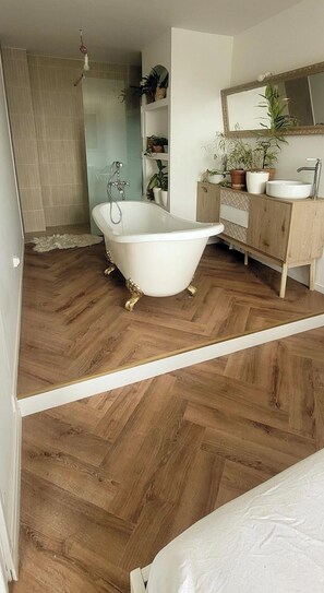 Ein Badezimmer mit freistehender Badewanne, einem Waschbecken und einem Spiegel.