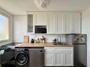 Eine kompakte Küche mit weißen Schränken, einer Mikrowelle, einem Spülbecken und einem Kühlschrank.