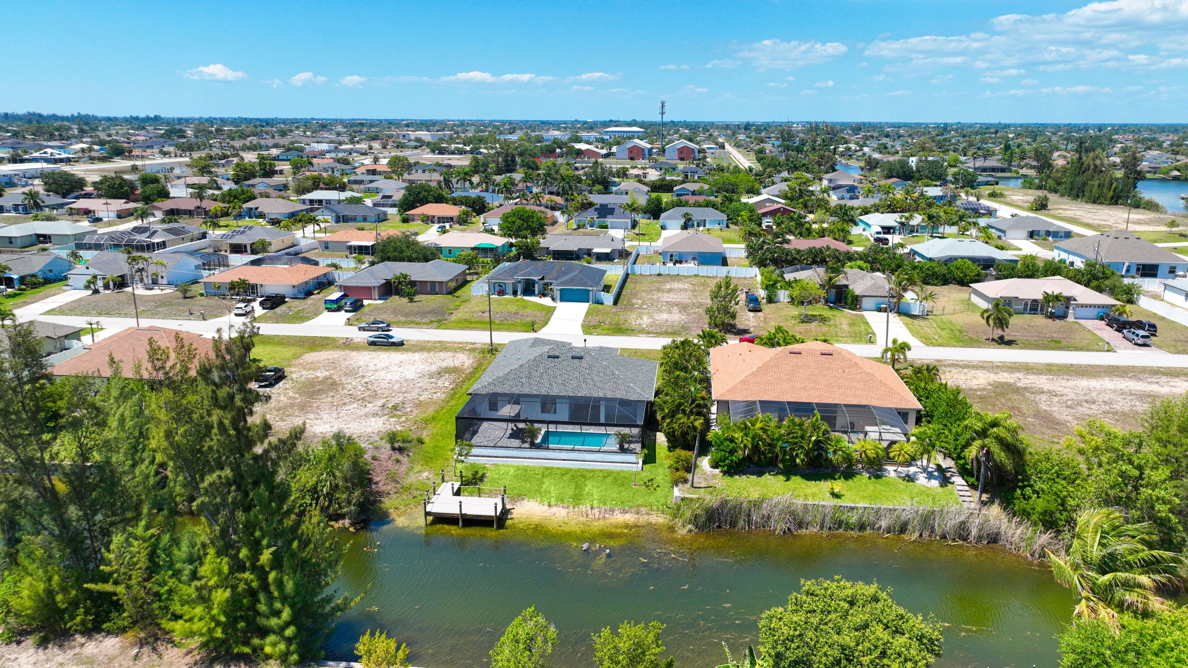 A residential area with houses, a small body of water, and a clear sky.