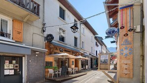 Calle adoquinada con mesas al aire libre y un restaurante llamado 'Le Tire-Fesses'.