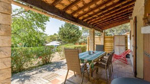 En uteplats med ett bord och stolar, en pergola ovanför och utsikt över den omgivande trädgården och träden.